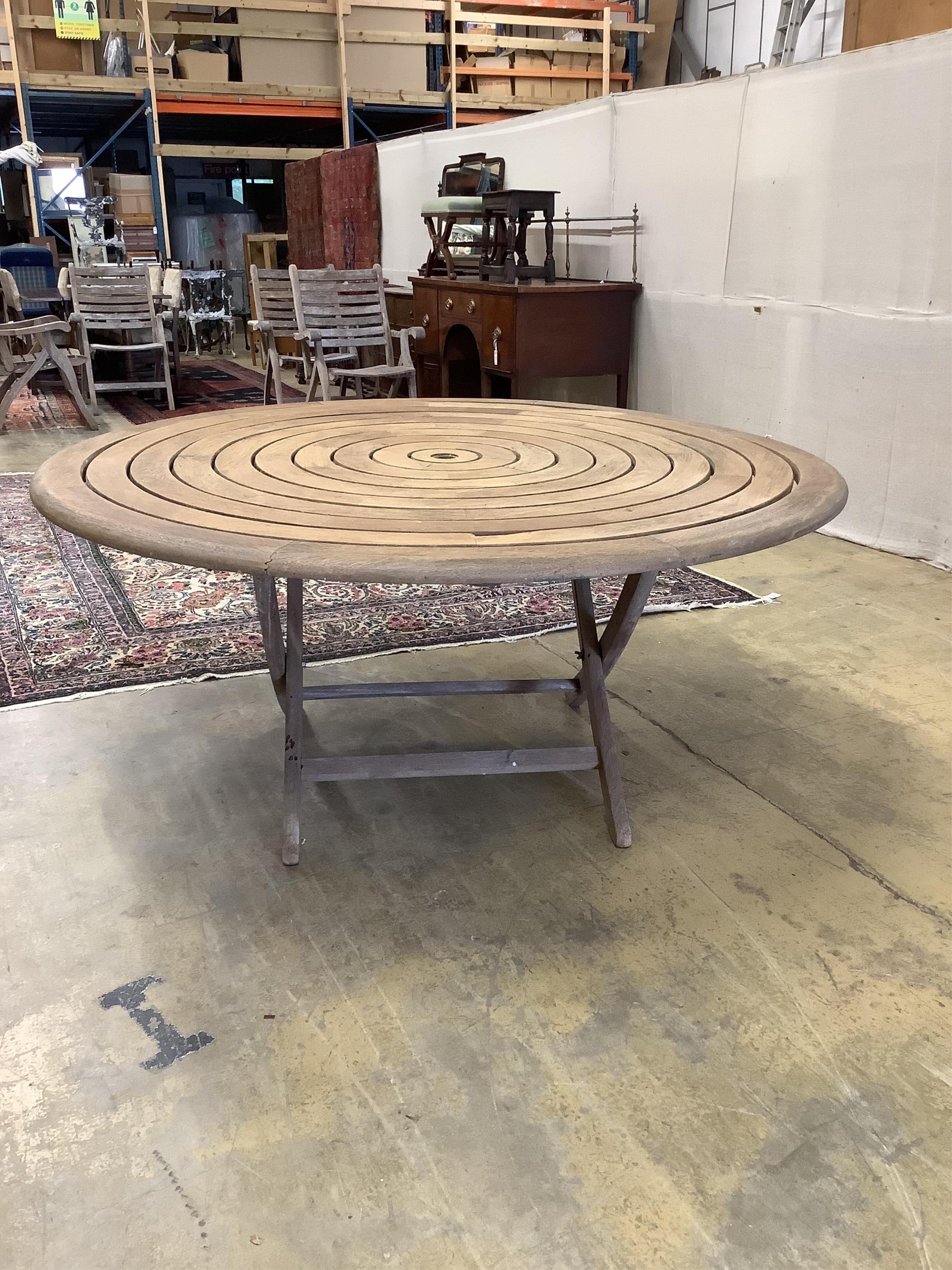 An Alexander Rose circular teak folding garden table with a set of four folding chairs. Condition - table fair, chairs more notably weathered